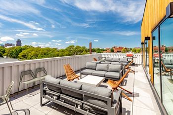 A patio with a table and chairs overlooking a city skyline.at Rowat Lofts, Des Moines, IA  